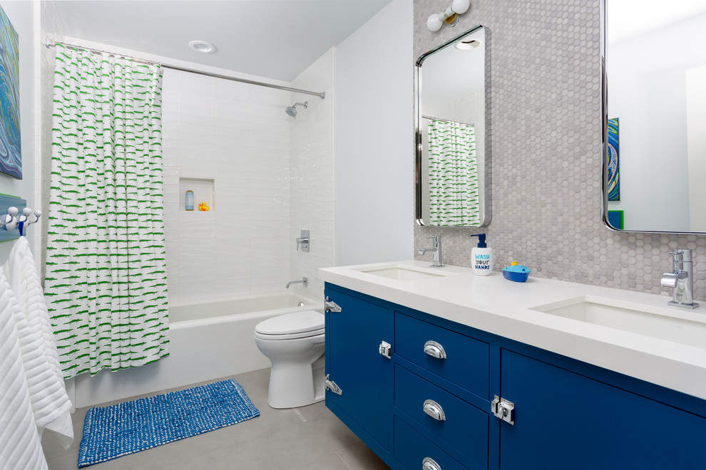 Idée de décoration pour une salle de bain design pour enfant avec un placard à porte plane, des portes de placard bleues, une baignoire en alcôve, un combiné douche/baignoire, un carrelage gris, un carrelage blanc, un mur blanc, sol en béton ciré, un lavabo encastré et une cabine de douche avec un rideau.