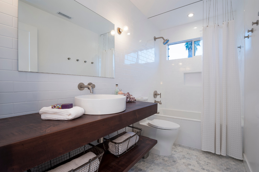 Example of a beach style white tile and subway tile mosaic tile floor bathroom design in San Diego with a vessel sink, open cabinets, dark wood cabinets, wood countertops and a two-piece toilet