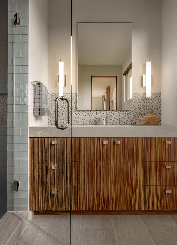 Imagen de cuarto de baño actual con armarios con paneles lisos, puertas de armario de madera oscura, baldosas y/o azulejos grises, baldosas y/o azulejos en mosaico, paredes beige y ducha con puerta con bisagras