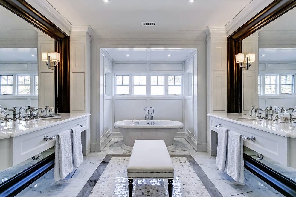 Пример оригинального дизайна: главная ванная комната в классическом стиле с фасадами с утопленной филенкой, белыми фасадами, отдельно стоящей ванной, белыми стенами, врезной раковиной, мраморным полом, столешницей из искусственного кварца и окном