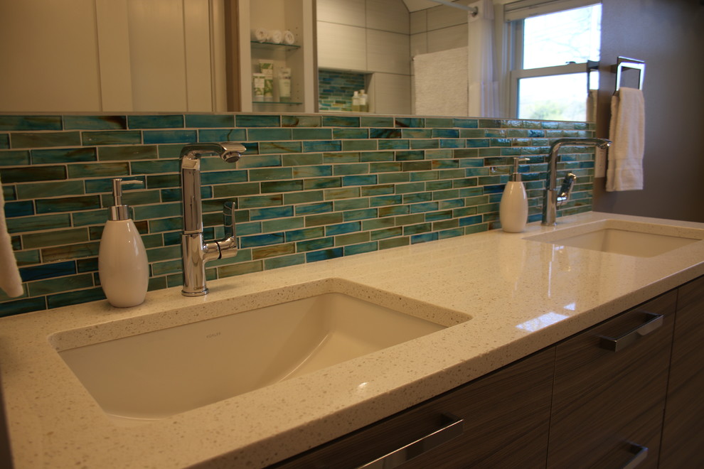 Пример оригинального дизайна: ванная комната в стиле модернизм с плоскими фасадами, серыми фасадами, ванной в нише, синей плиткой, плиткой из листового стекла, серыми стенами, полом из керамогранита, врезной раковиной и столешницей из искусственного кварца