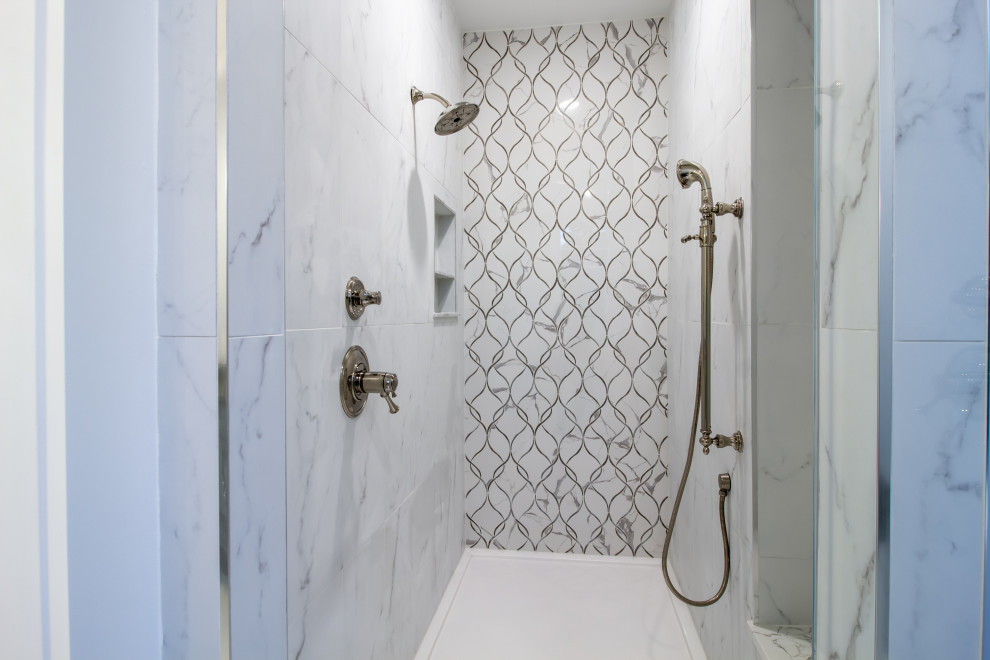 Стильный дизайн: большая главная ванная комната в стиле неоклассика (современная классика) с фасадами в стиле шейкер, серыми фасадами, угловой ванной, душем без бортиков, раздельным унитазом, серой плиткой, керамической плиткой, серыми стенами, полом из керамической плитки, врезной раковиной, столешницей из гранита, белым полом, душем с распашными дверями, серой столешницей, нишей, тумбой под две раковины и встроенной тумбой - последний тренд