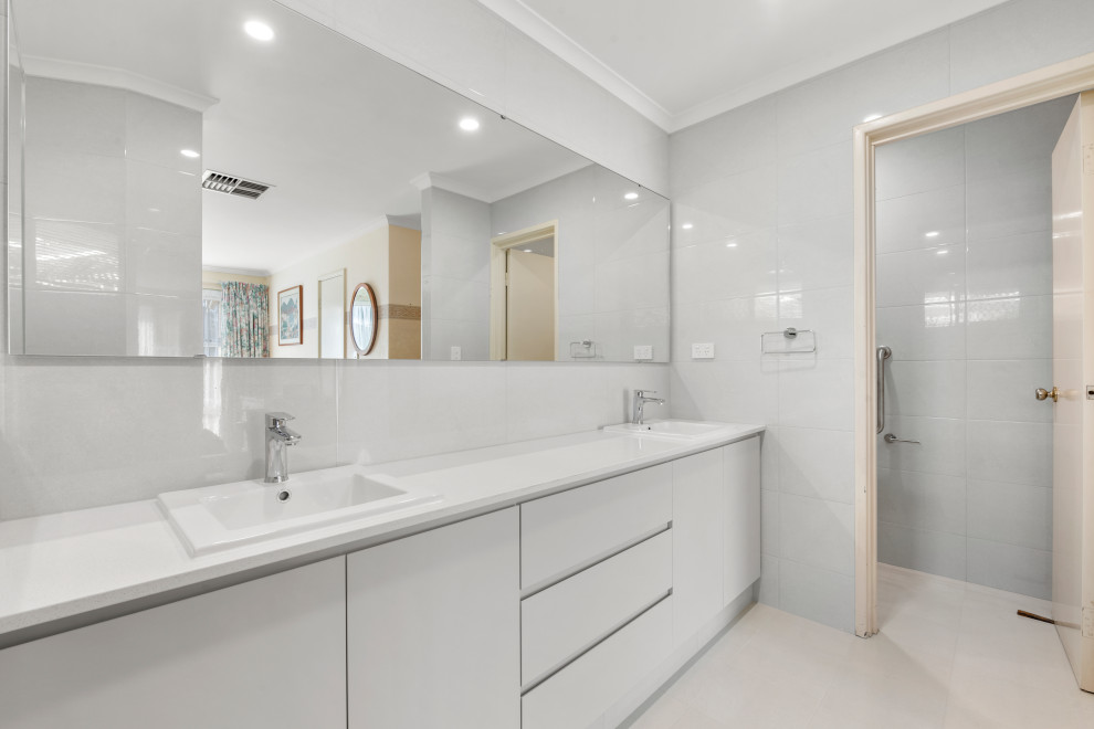 This is an example of a small contemporary shower room bathroom in Perth with shaker cabinets, white cabinets, a corner shower, a one-piece toilet, white tiles, white walls, a built-in sink, white floors, an open shower, white worktops, an enclosed toilet, double sinks and a built in vanity unit.