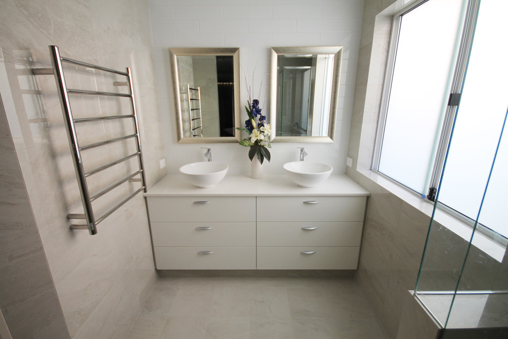Aménagement d'une salle de bain contemporaine avec un placard à porte plane, des portes de placard blanches, une vasque et un plan de toilette en quartz modifié.