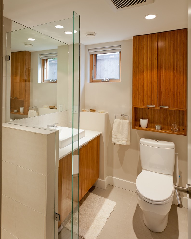 Photo of a small contemporary bathroom in Vancouver with flat-panel cabinets, medium wood cabinets, engineered stone worktops, a corner shower, a two-piece toilet, a vessel sink, white tiles, porcelain tiles, porcelain flooring and beige walls.