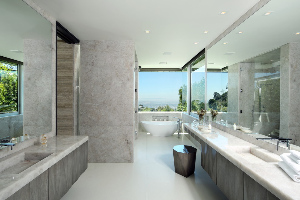 Großes Modernes Badezimmer En Suite mit flächenbündigen Schrankfronten, grauen Schränken, freistehender Badewanne, Duschnische, grauer Wandfarbe, Keramikboden, integriertem Waschbecken, Marmor-Waschbecken/Waschtisch, beigem Boden und Falttür-Duschabtrennung in Los Angeles