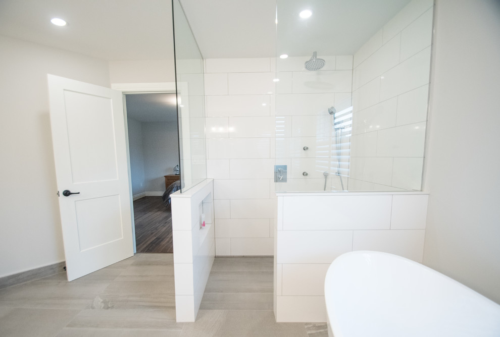This is an example of a medium sized classic ensuite bathroom in Toronto with white cabinets, a freestanding bath, a built-in shower, a two-piece toilet, white tiles, porcelain tiles, porcelain flooring, a submerged sink, grey floors, an open shower, white worktops, recessed-panel cabinets, grey walls and marble worktops.