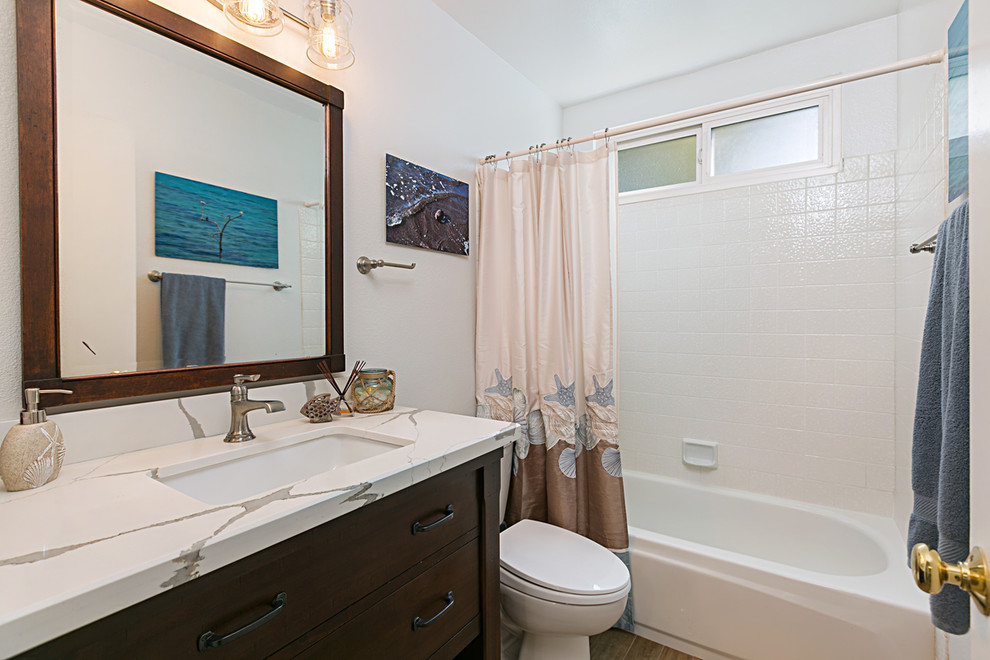 Bathroom - mid-sized coastal 3/4 white tile brown floor, wood-look tile floor and single-sink bathroom idea in San Diego with flat-panel cabinets, brown cabinets, a two-piece toilet, white walls, a drop-in sink, quartzite countertops, white countertops and a built-in vanity