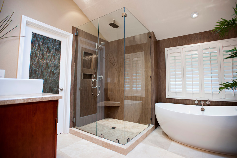 Cette photo montre une grande salle de bain principale tendance en bois brun avec un placard à porte affleurante, une baignoire indépendante, une douche d'angle, un mur beige, un sol en carrelage de céramique, une vasque, un plan de toilette en calcaire et une cabine de douche à porte battante.