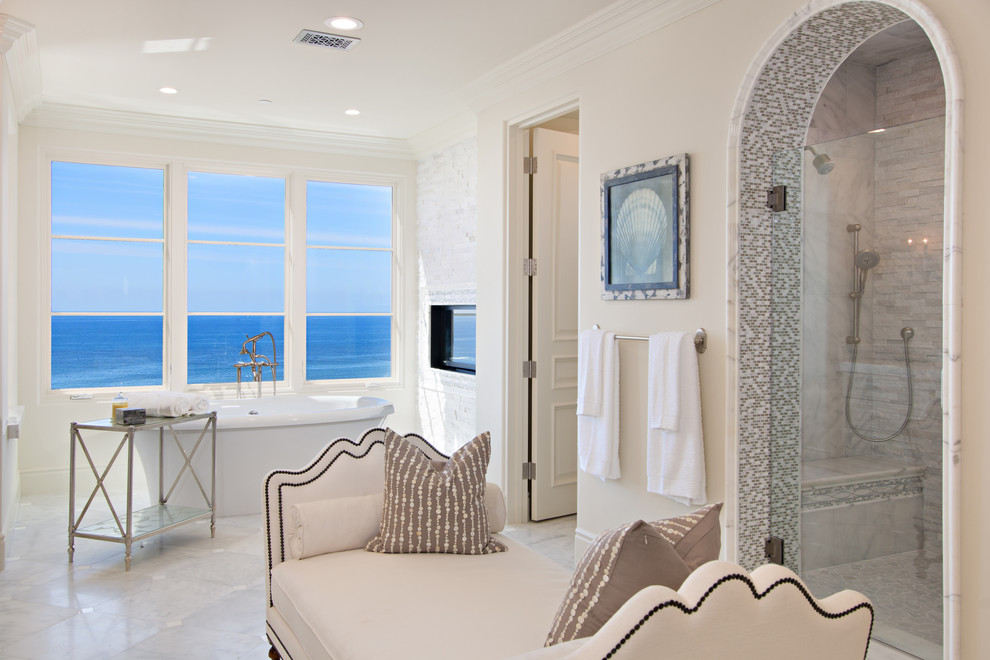 Inspiration for a large coastal ensuite bathroom in San Diego with a freestanding bath, an alcove shower, a two-piece toilet, grey tiles, white tiles, stone tiles, beige walls, marble flooring, grey floors and a hinged door.