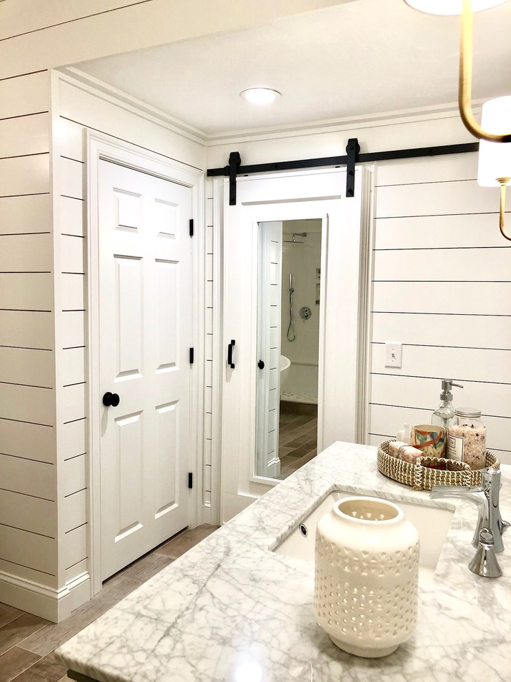 На фото: большая главная ванная комната в стиле кантри с фасадами с утопленной филенкой, серыми фасадами, белыми стенами, светлым паркетным полом, врезной раковиной, столешницей из гранита, коричневым полом и белой столешницей с
