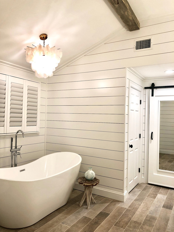 Идея дизайна: большая главная ванная комната в стиле кантри с фасадами с утопленной филенкой, серыми фасадами, отдельно стоящей ванной, белыми стенами, светлым паркетным полом, врезной раковиной, столешницей из гранита, коричневым полом и белой столешницей