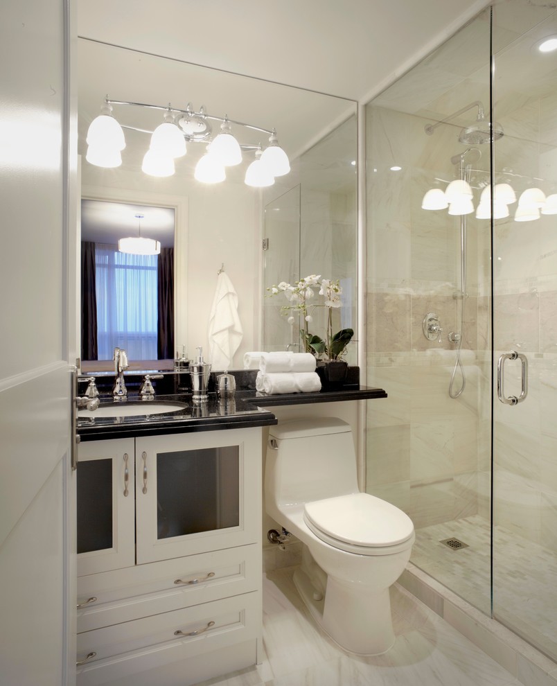 Modelo de cuarto de baño tradicional renovado con lavabo bajoencimera, armarios tipo vitrina, puertas de armario blancas, encimera de granito, ducha abierta, sanitario de una pieza y baldosas y/o azulejos blancos