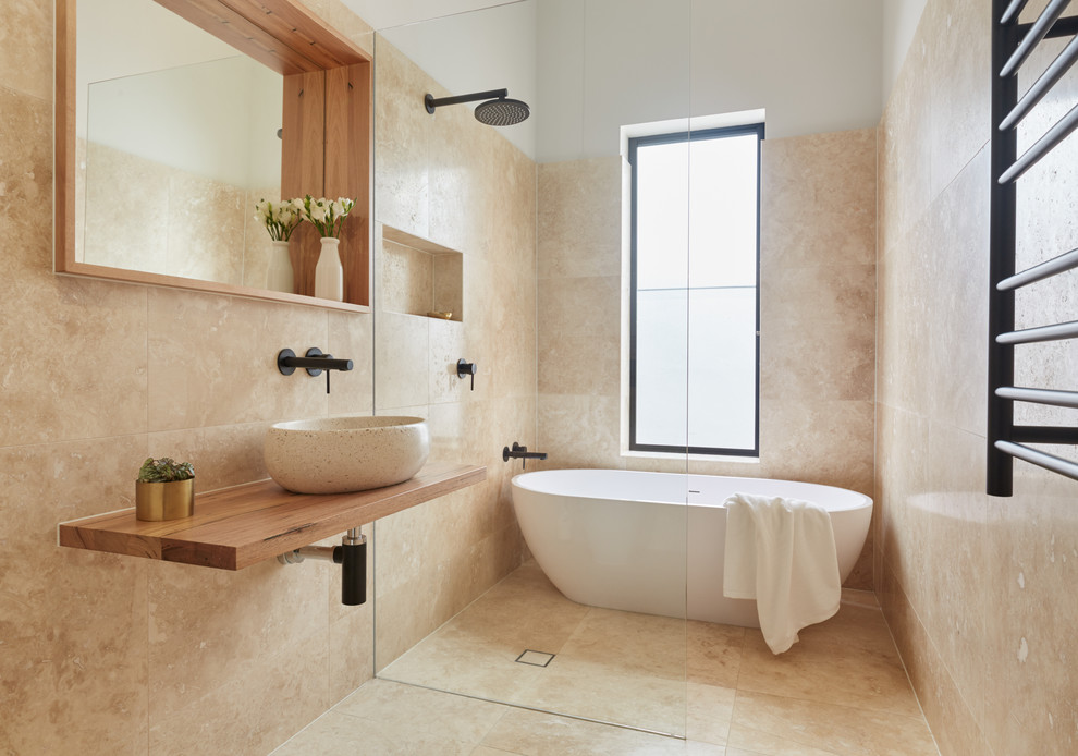 Idéer för att renovera ett litet funkis brun brunt badrum med dusch, med luckor med glaspanel, bruna skåp, ett fristående badkar, en öppen dusch, beige kakel, ett fristående handfat, träbänkskiva och med dusch som är öppen