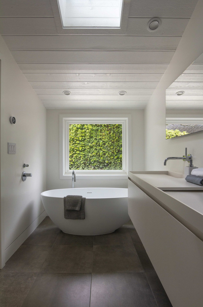 Пример оригинального дизайна: главная ванная комната среднего размера в стиле кантри с фасадами с утопленной филенкой, белыми фасадами, отдельно стоящей ванной, раковиной с несколькими смесителями и столешницей из искусственного камня