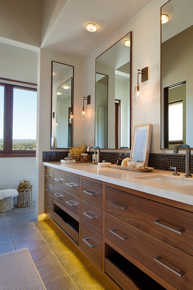 Стильный дизайн: ванная комната в современном стиле с плоскими фасадами, фасадами цвета дерева среднего тона, коричневой плиткой, плиткой мозаикой, бетонным полом, врезной раковиной и столешницей из известняка - последний тренд