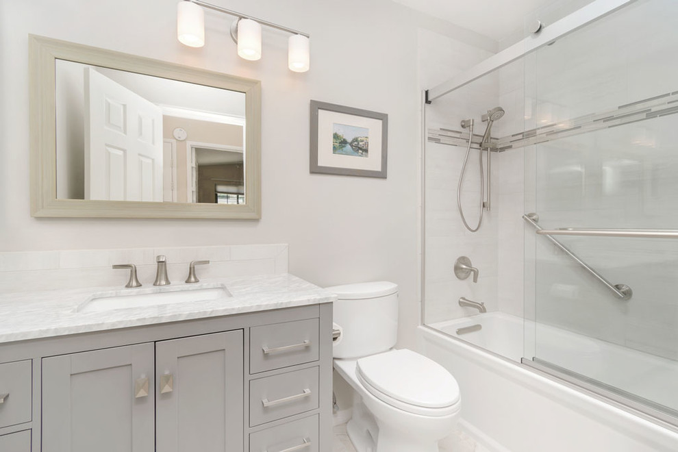 Foto på ett litet funkis vit en-suite badrum, med möbel-liknande, grå skåp, ett badkar i en alkov, en toalettstol med separat cisternkåpa, grå kakel, grå väggar, klinkergolv i porslin, ett undermonterad handfat och bänkskiva i kvarts
