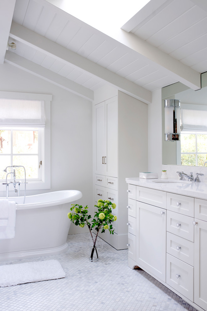 Immagine di una stanza da bagno padronale costiera di medie dimensioni con ante in stile shaker, ante bianche, vasca freestanding, pareti bianche, lavabo sottopiano, pavimento grigio e top bianco