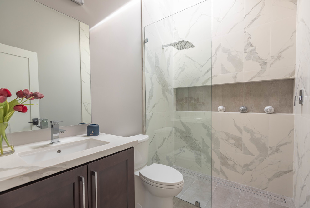 Пример оригинального дизайна: ванная комната среднего размера в стиле ретро с фасадами в стиле шейкер, серыми фасадами, душем без бортиков, белой плиткой, плиткой из сланца, серыми стенами, полом из керамической плитки, врезной раковиной, столешницей из искусственного кварца, серым полом, душем с распашными дверями, белой столешницей и унитазом-моноблоком