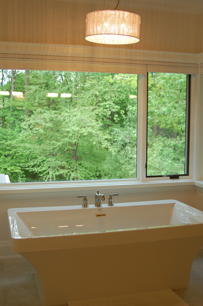 На фото: главная ванная комната в стиле неоклассика (современная классика) с отдельно стоящей ванной и белыми стенами с