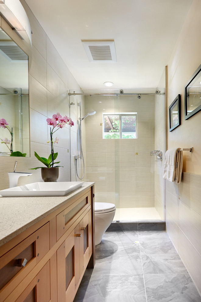 Exemple d'une salle de bain tendance en bois clair de taille moyenne avec un placard avec porte à panneau encastré, WC à poser, un carrelage beige, des carreaux de porcelaine, un mur beige, un sol en ardoise, une vasque et un plan de toilette en stratifié.