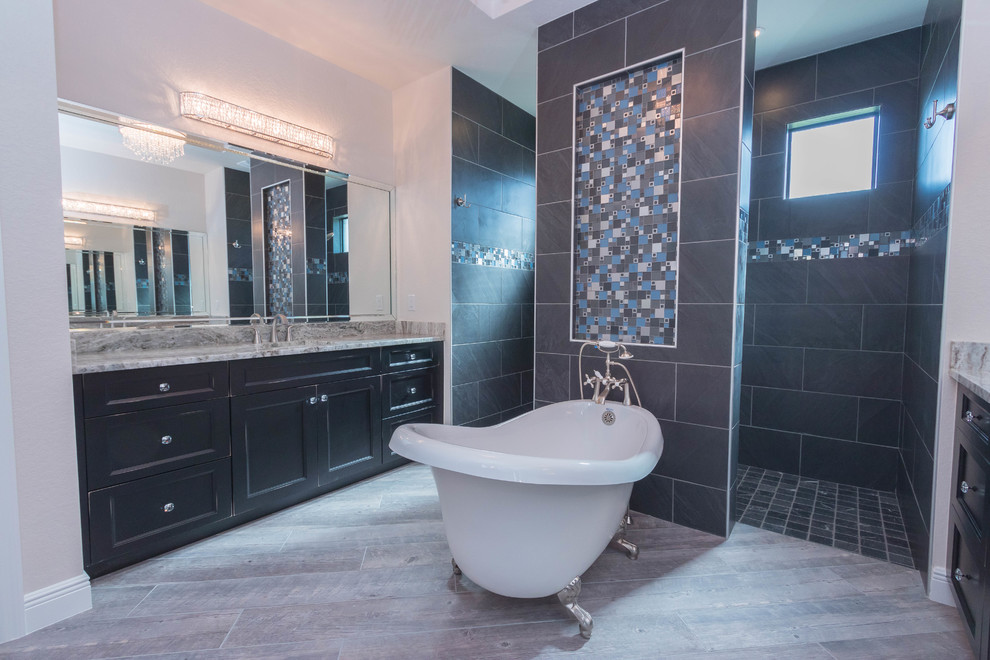This is an example of a large bohemian ensuite bathroom in Other with freestanding cabinets, black cabinets, a claw-foot bath, a walk-in shower, black tiles, grey walls, porcelain flooring, a submerged sink, granite worktops, grey floors and an open shower.