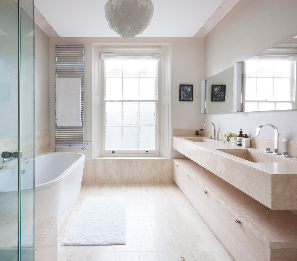 Modelo de cuarto de baño actual de tamaño medio con bañera exenta, paredes beige, encimera de mármol, suelo de mármol y encimeras beige