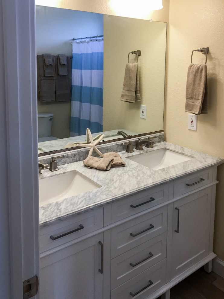 Foto di una stanza da bagno stile marinaro di medie dimensioni con ante in stile shaker, ante bianche, pareti beige, pavimento con piastrelle in ceramica, lavabo sottopiano e top in marmo