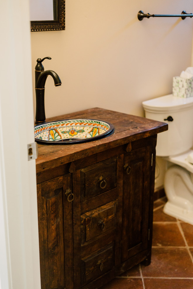 Inredning av ett medelhavsstil litet badrum med dusch, med möbel-liknande, skåp i slitet trä, en dusch i en alkov, en toalettstol med separat cisternkåpa, vit kakel, keramikplattor, beige väggar, klinkergolv i terrakotta, ett fristående handfat, träbänkskiva och brunt golv