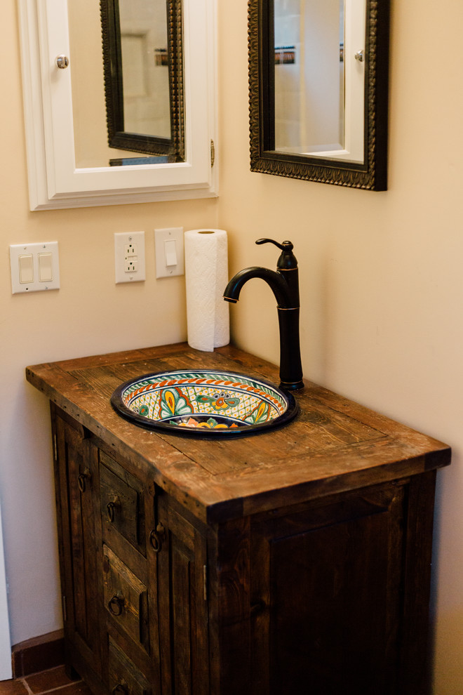 Cette image montre une petite salle de bain méditerranéenne en bois vieilli avec un placard en trompe-l'oeil, WC séparés, un carrelage blanc, des carreaux de céramique, un mur beige, tomettes au sol, une vasque, un plan de toilette en bois et un sol marron.