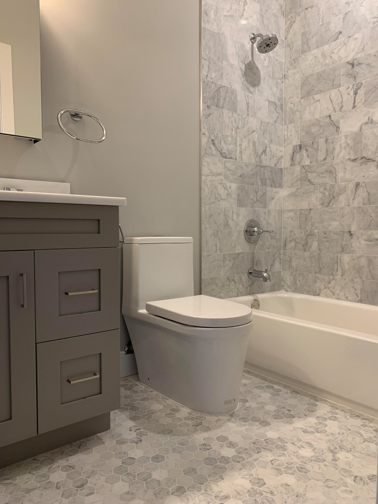Réalisation d'une salle de bain tradition avec des portes de placard grises, WC à poser, un sol en marbre, un lavabo encastré, un plan de toilette en quartz modifié et un plan de toilette blanc.