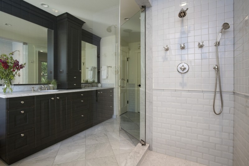 Corner shower - mid-sized traditional master white tile and stone tile marble floor corner shower idea in Chicago with raised-panel cabinets, dark wood cabinets, white walls, an undermount sink and marble countertops