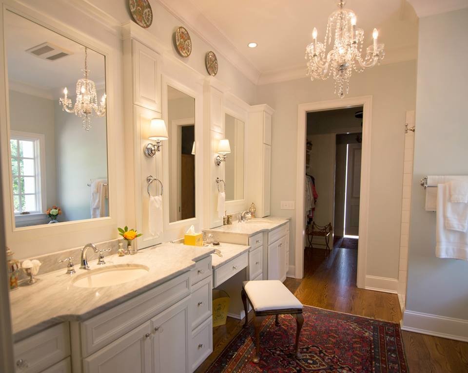 Réalisation d'une salle de bain principale tradition de taille moyenne avec un placard à porte affleurante, des portes de placard blanches, un mur blanc, un sol en bois brun, un lavabo encastré et un plan de toilette en marbre.