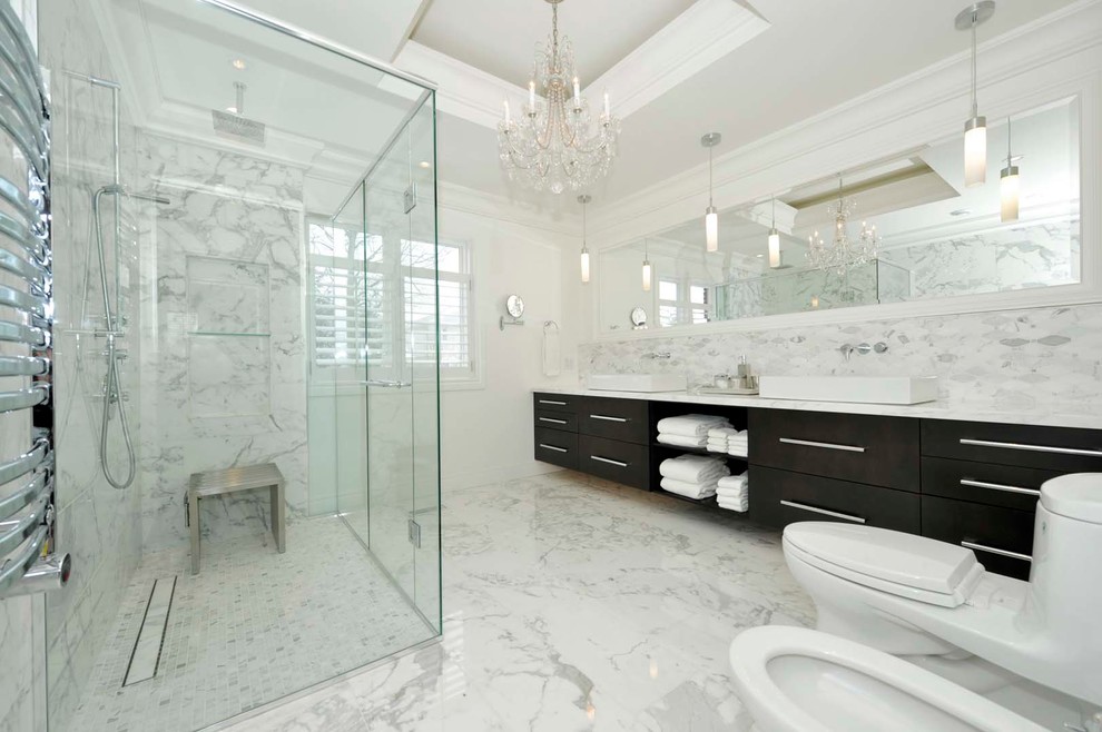 Cette image montre une salle de bain design avec un placard à porte plane, des portes de placard noires, une douche d'angle, un carrelage blanc, un mur blanc, une vasque et une cabine de douche à porte battante.