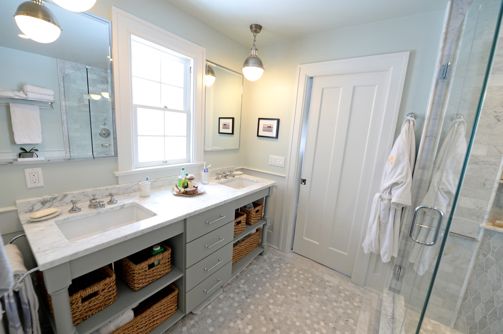 Klassisk inredning av ett mellanstort badrum, med ett undermonterad handfat, möbel-liknande, grå skåp, marmorbänkskiva, en hörndusch, en toalettstol med separat cisternkåpa, grå kakel, grå väggar och marmorgolv