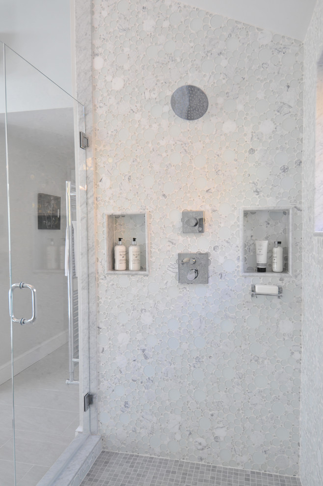 Exempel på ett stort modernt blå blått en-suite badrum, med blå skåp, ett fristående badkar, en toalettstol med hel cisternkåpa, vit kakel, glaskakel, ett integrerad handfat, bänkskiva i glas, beiget golv, dusch med gångjärnsdörr, släta luckor, en dusch i en alkov, grå väggar och klinkergolv i porslin