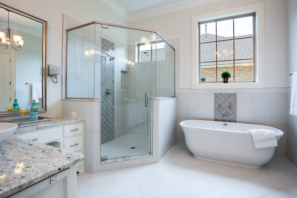 Пример оригинального дизайна: главная ванная комната среднего размера в стиле неоклассика (современная классика) с фасадами с выступающей филенкой, белыми фасадами, отдельно стоящей ванной, угловым душем, унитазом-моноблоком, серой плиткой, керамогранитной плиткой, белыми стенами, полом из керамической плитки, настольной раковиной и столешницей из гранита