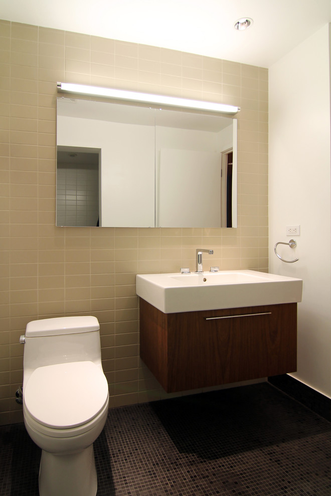 This is an example of a medium sized modern shower room bathroom in New York with an integrated sink, flat-panel cabinets, dark wood cabinets, a one-piece toilet, beige tiles, porcelain tiles, beige walls and ceramic flooring.