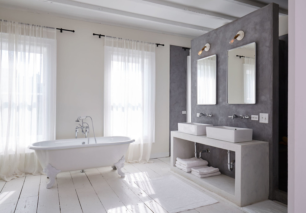 Cette image montre une grande salle de bain principale design avec une vasque, une baignoire sur pieds, un mur gris et parquet peint.