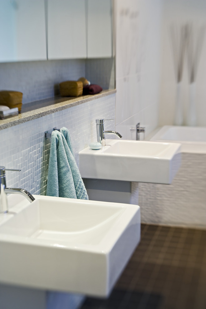 ブリスベンにある高級な小さなコンテンポラリースタイルのおしゃれなマスターバスルーム (壁付け型シンク、ガラス扉のキャビネット、白いキャビネット、クオーツストーンの洗面台、和式浴槽、アルコーブ型シャワー、一体型トイレ	、白いタイル、セラミックタイル、白い壁、磁器タイルの床) の写真