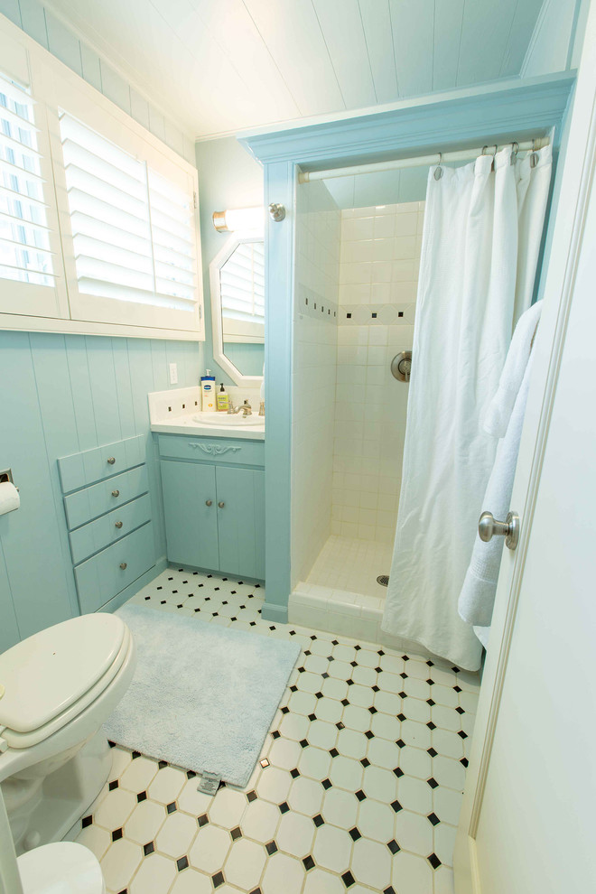 Idéer för att renovera ett mellanstort vintage badrum med dusch, med ett väggmonterat handfat, släta luckor, blå skåp, ett fristående badkar, en dusch i en alkov, en toalettstol med hel cisternkåpa, blå kakel, keramikplattor, gula väggar och klinkergolv i keramik