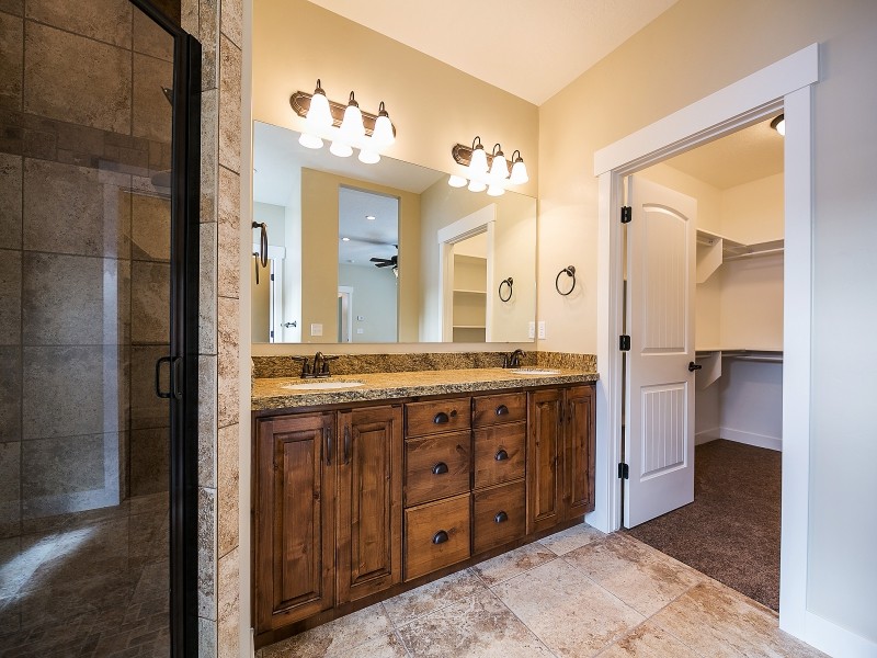 Foto på ett stort amerikanskt en-suite badrum, med luckor med upphöjd panel, skåp i mellenmörkt trä, granitbänkskiva, ett hörnbadkar, en hörndusch, beige kakel, keramikplattor, beige väggar och klinkergolv i keramik