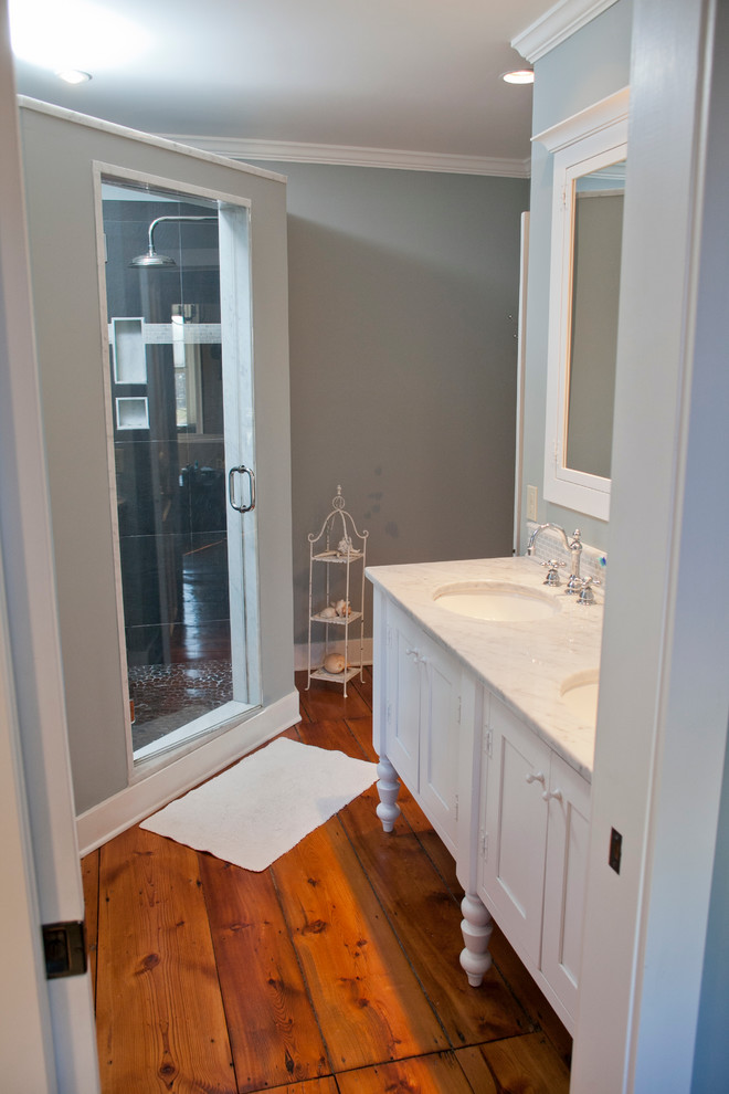 Corner shower - mid-sized cottage master gray tile and mosaic tile medium tone wood floor corner shower idea in Philadelphia with an undermount sink, shaker cabinets, white cabinets, marble countertops, a two-piece toilet and green walls