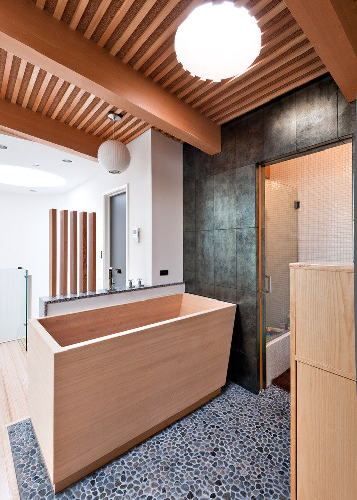 Idée de décoration pour une salle de bain design avec un bain japonais, une plaque de galets et un sol en galet.