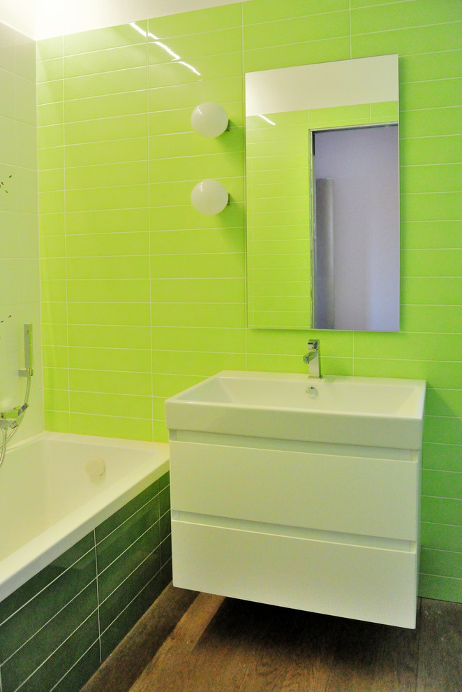 Modelo de cuarto de baño principal contemporáneo de tamaño medio con sanitario de pared, baldosas y/o azulejos de cerámica, lavabo suspendido, bañera encastrada, baldosas y/o azulejos verdes, paredes verdes y suelo de madera oscura