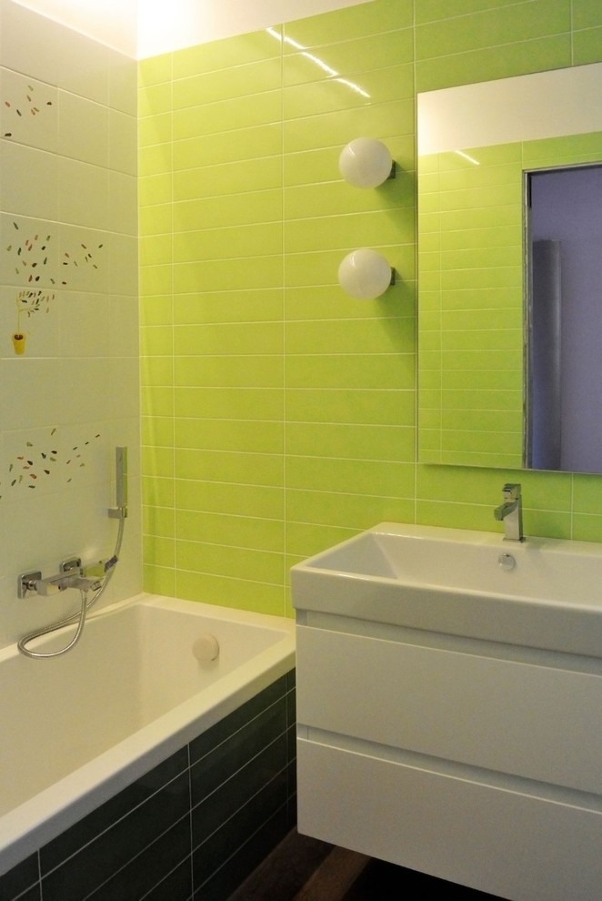 Idéer för mellanstora funkis en-suite badrum, med ett platsbyggt badkar, en vägghängd toalettstol, grön kakel, keramikplattor, gröna väggar, mörkt trägolv och ett väggmonterat handfat