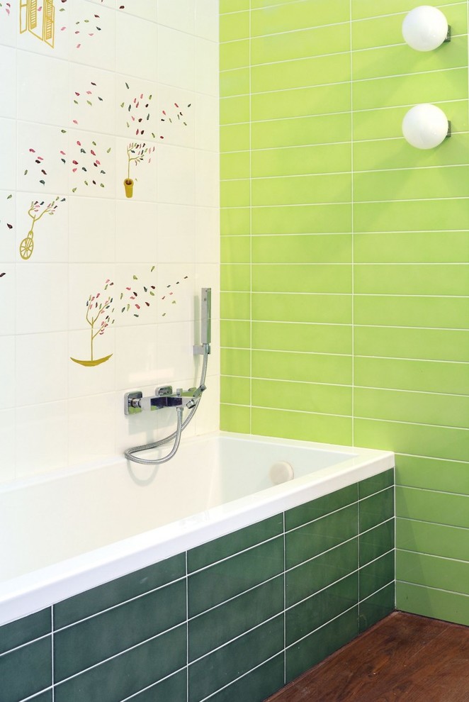 Imagen de cuarto de baño principal contemporáneo de tamaño medio con sanitario de pared, baldosas y/o azulejos de cerámica, lavabo suspendido, bañera encastrada, baldosas y/o azulejos verdes, paredes verdes y suelo de madera oscura