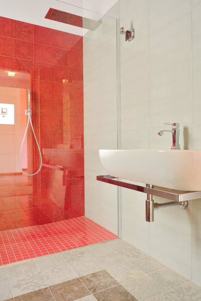 Foto på ett mellanstort funkis badrum med dusch, med ett väggmonterat handfat, en kantlös dusch, grå kakel, keramikplattor, grå väggar och klinkergolv i porslin