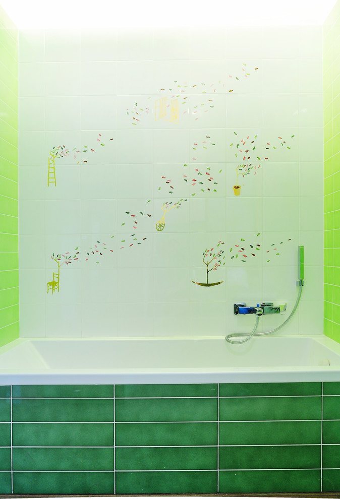 Imagen de cuarto de baño principal actual de tamaño medio con sanitario de pared, baldosas y/o azulejos de cerámica, lavabo suspendido, bañera encastrada, baldosas y/o azulejos verdes, paredes verdes y suelo de madera oscura