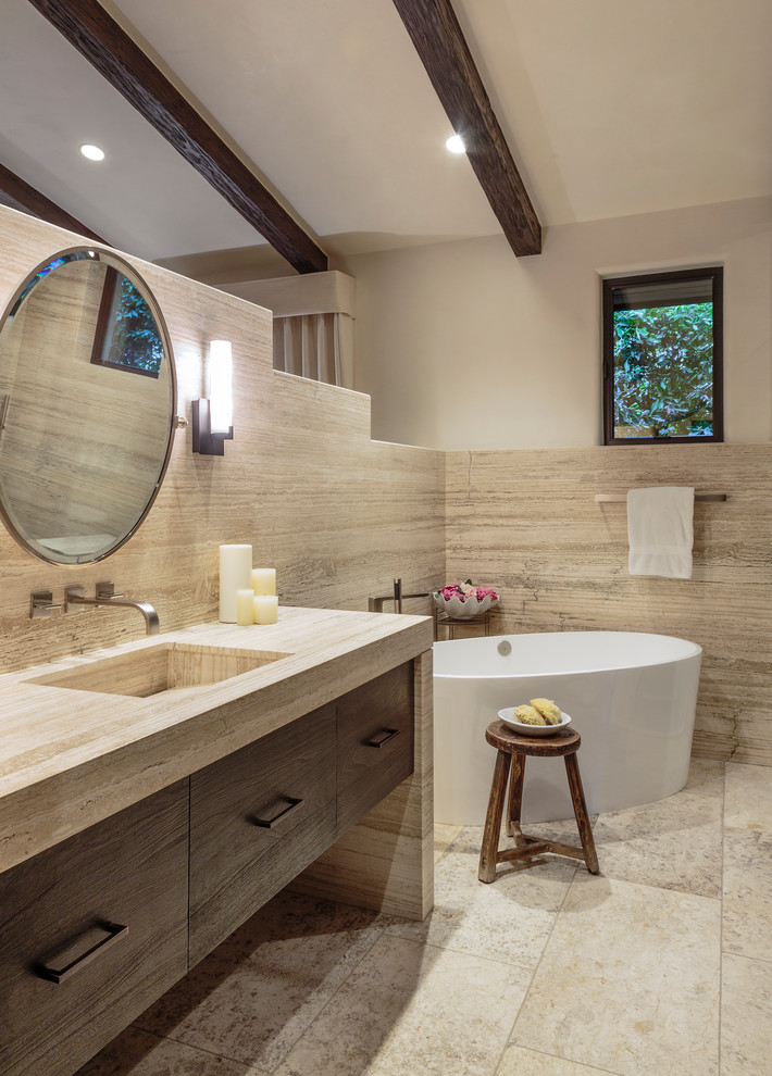 Réalisation d'une salle de bain principale design en bois brun avec un placard à porte plane, une baignoire indépendante, un mur blanc, un lavabo encastré, un sol beige et un plan de toilette beige.